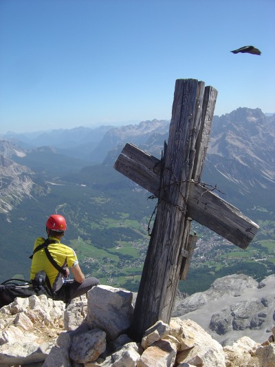 La croce della cima Tofana di Dentro, un corvazzo ed un escursionista.