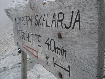 Con la testa tra le nuvole, a 2200 metri. Il cartello ci invita a raggiungere in 40 minuti il Rifugio Petra Skalarja.