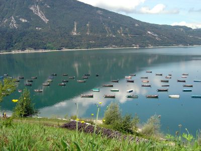 Vista sul lago di Santa Croce e sulle barche multicolore presso la spiaggetta in zona Poiatte.