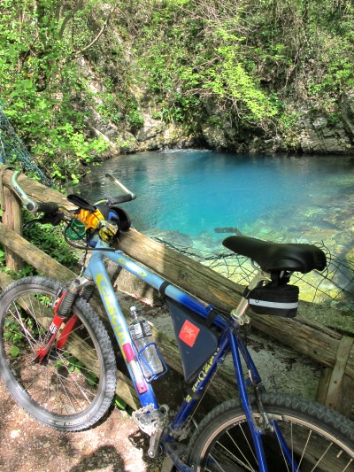 Appoggio la mtb allo steccato e appena alzo lo sguardo resto di sasso, davanti ad un azzurro così intenso da togliere il fiato. Ecco le sorgenti del Meschio, unico punto di estrema libertà del fiume, che praticamente viene subito imbrigliato ed accompagnato a valle.