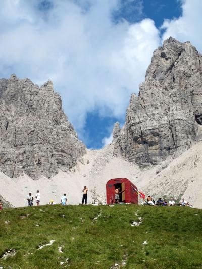 Alle nostre spalle un continuo andirivieni da e per il piccolo bivacco Perugini. Camminatori ed arrampicatori sciamano come api, tutto attorno al piccolo ricovero rosso.